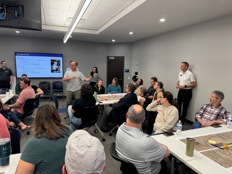 people gathered around maps on tables listening to speaker