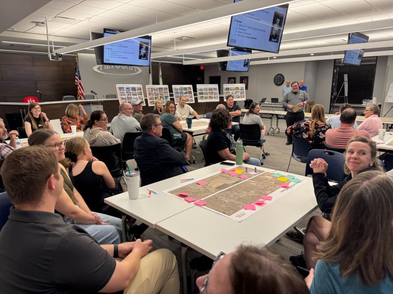 People gathered around maps on tables discussing and smiling